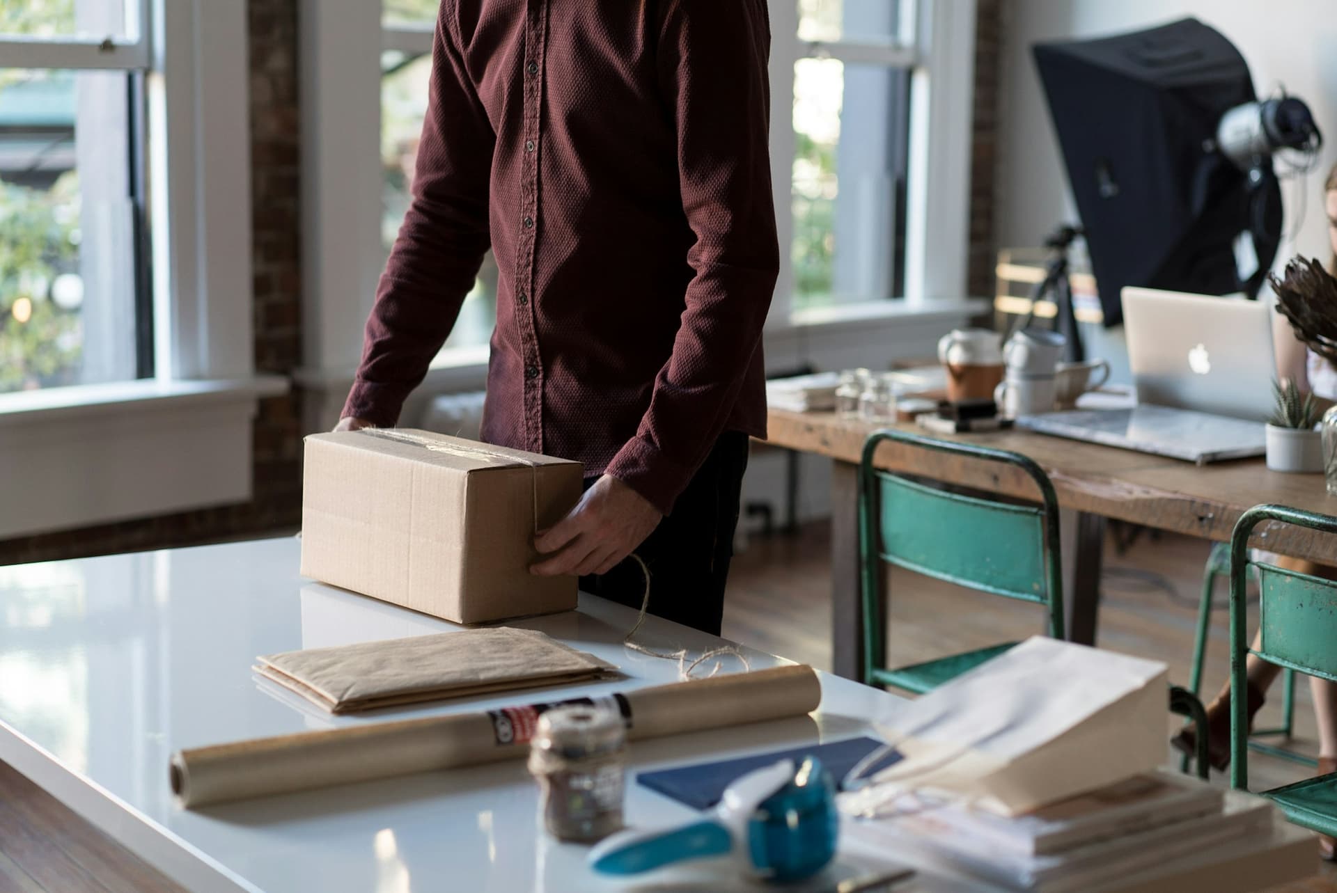 A business owner packing an order into a cardboard box at a studio worktable
