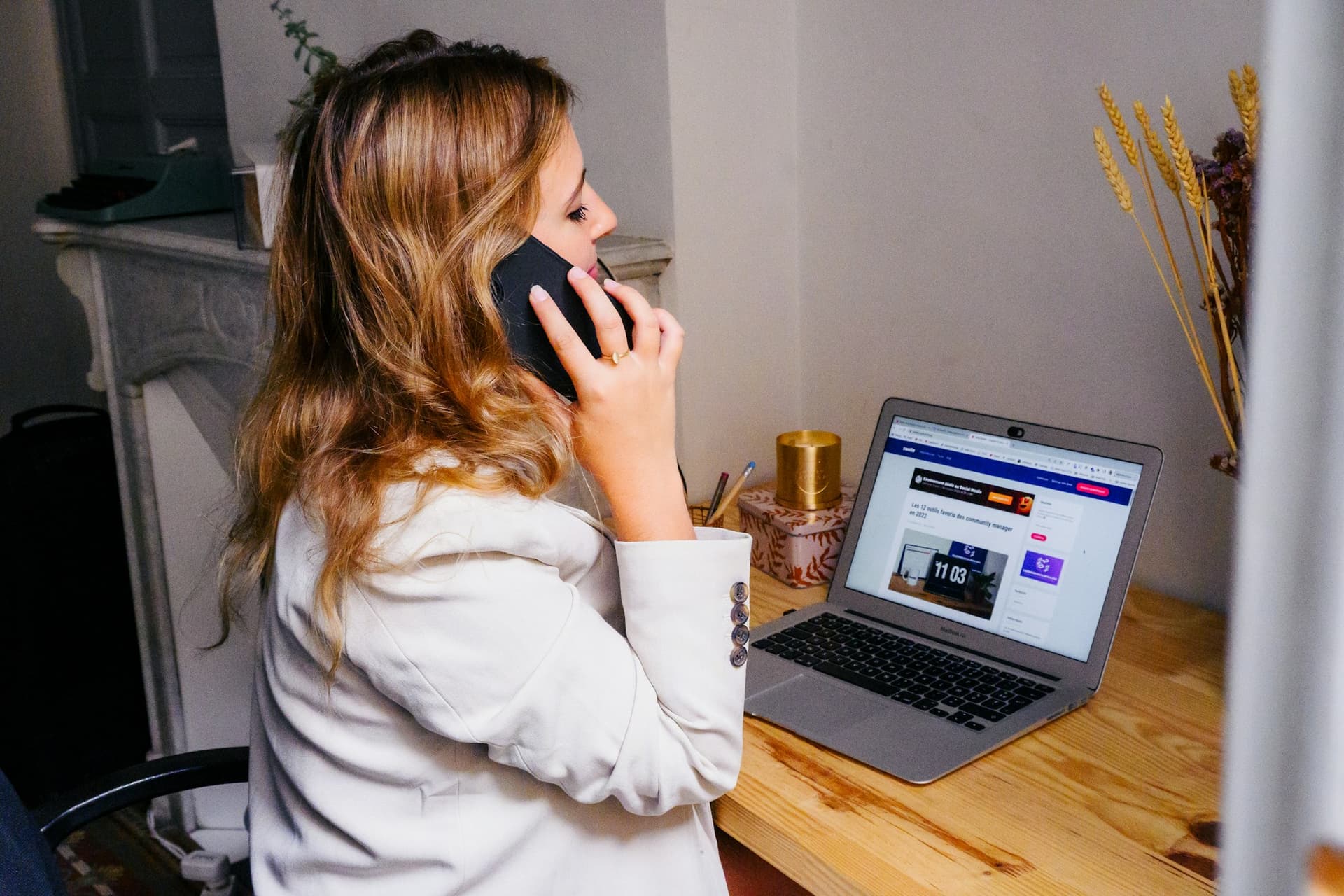 A business owner on a phone call at her desk with a laptop open