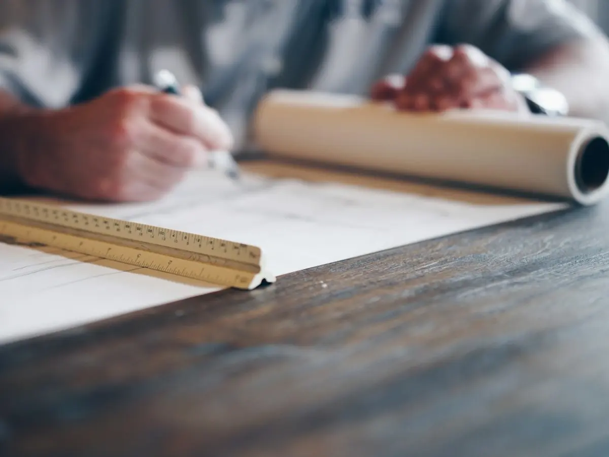 Hand drafting on a set of building plans with a ruler