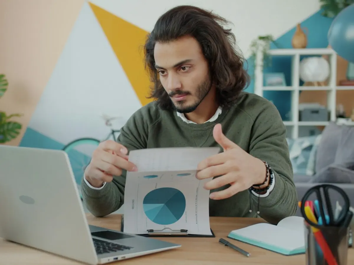 Contractor reviewing a printed report at his laptop