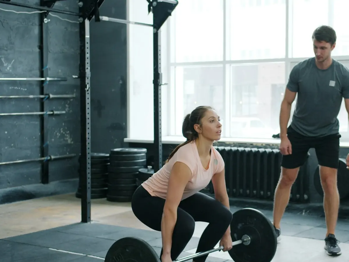 Personal trainer coaching a client through a barbell lift