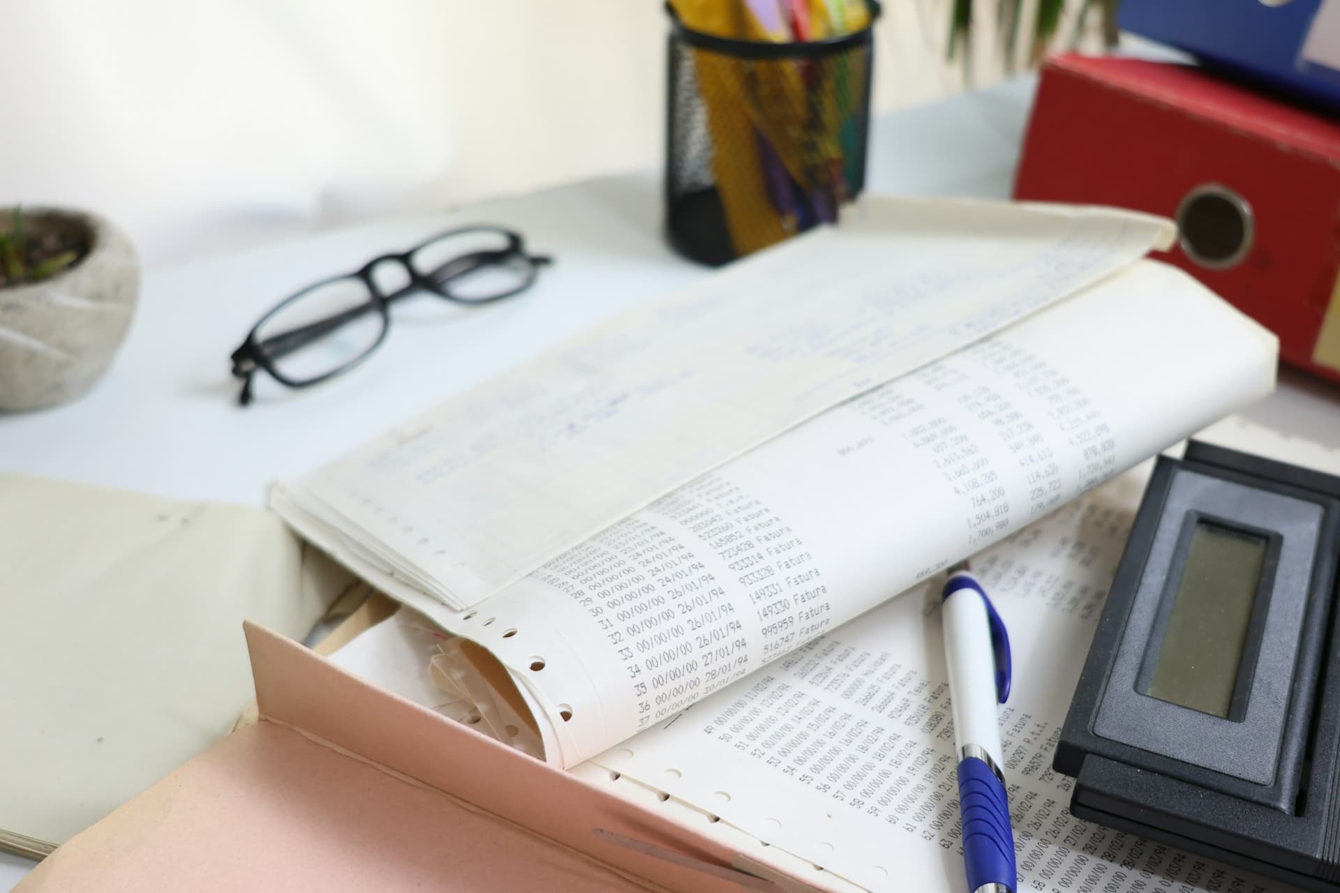 A printed general ledger open on a desk beside a calculator and pen