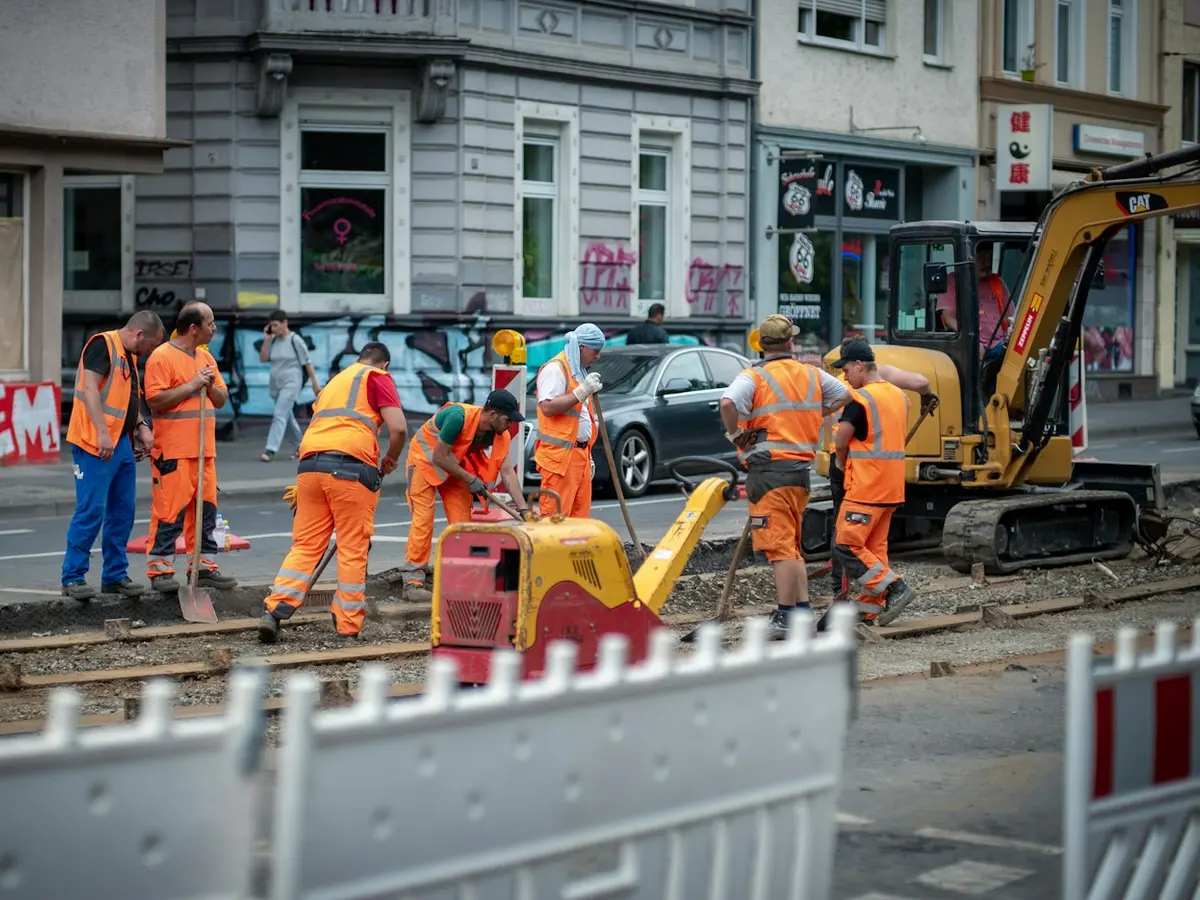 Construction crew in high-visibility gear working beside an excavator