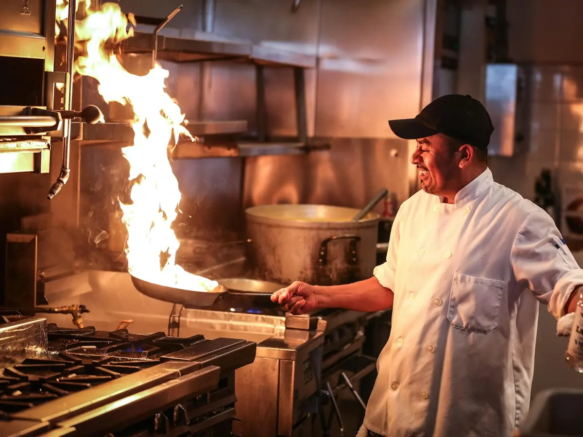 Chef cooking over a flaming range in a restaurant kitchen