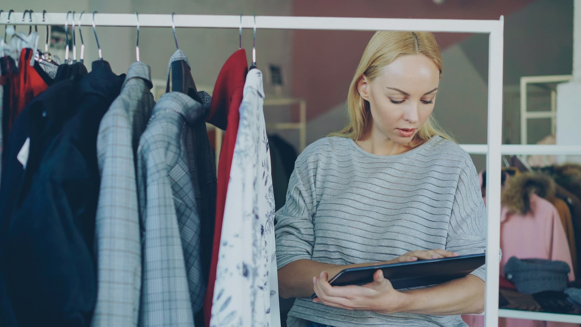 A boutique owner reviewing her own company file on a tablet in her store