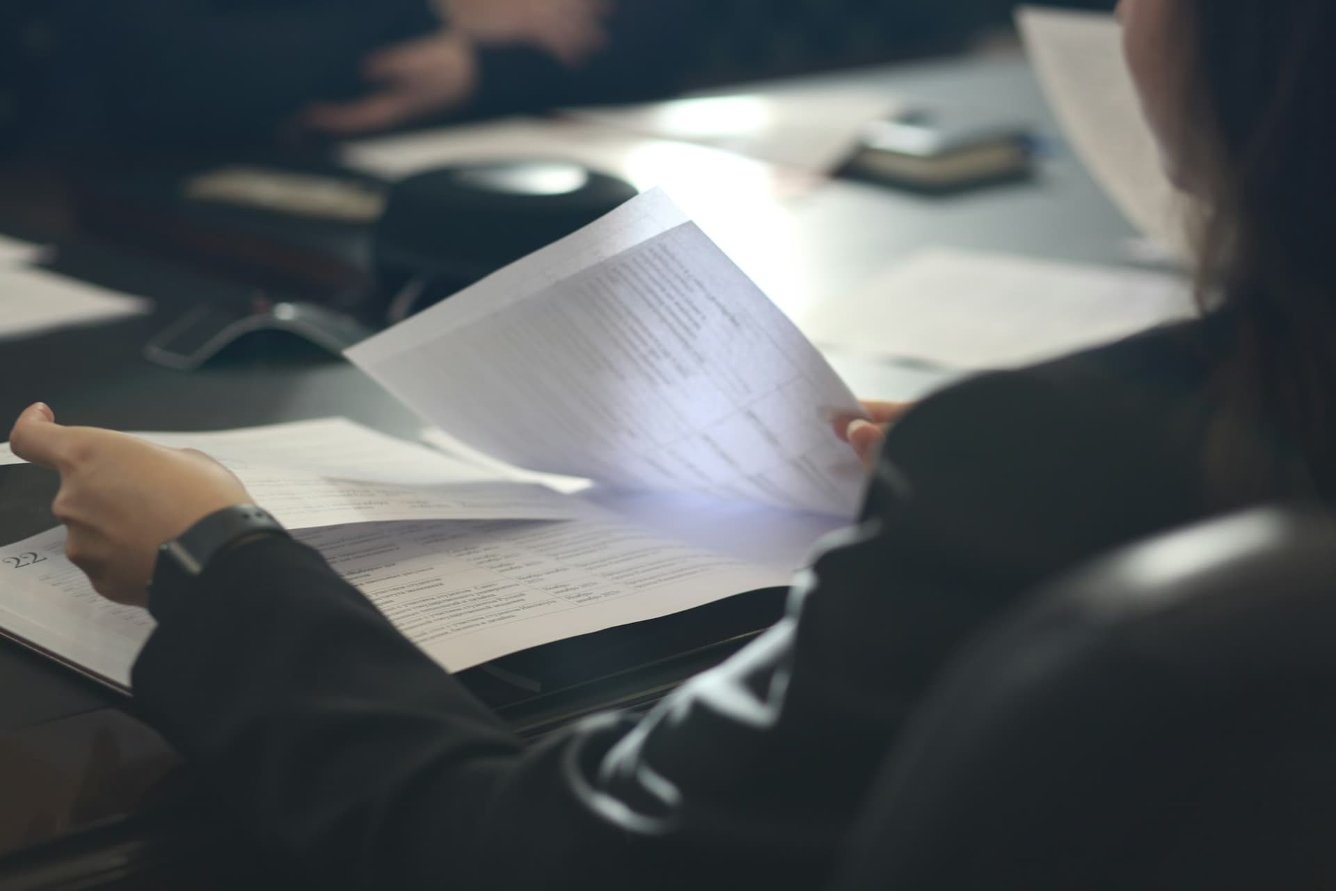 A business owner reading through a printed monthly report at a desk