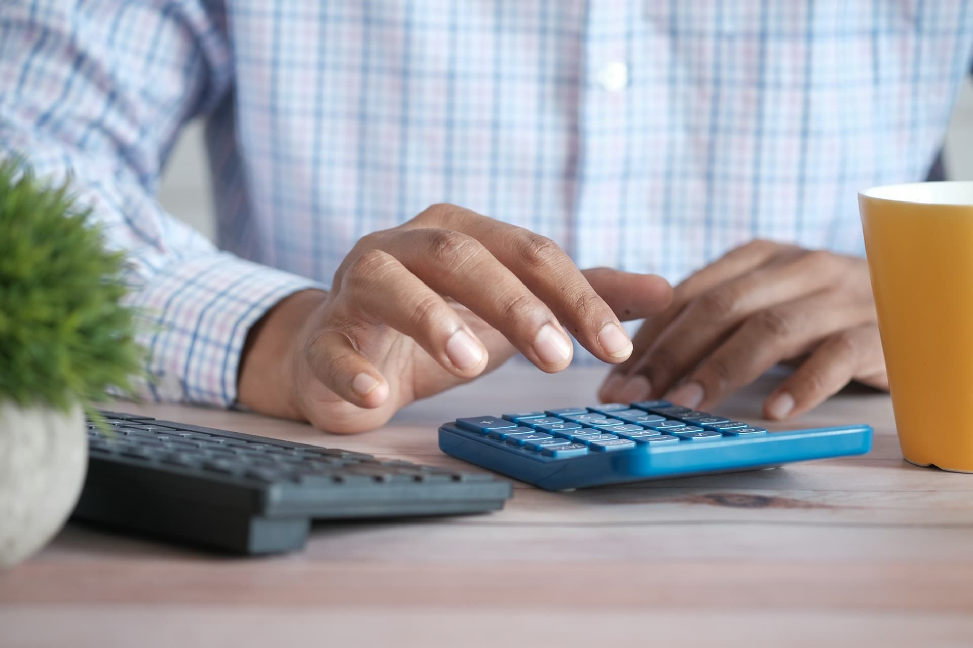 Hands working out estimated tax figures on a desk calculator